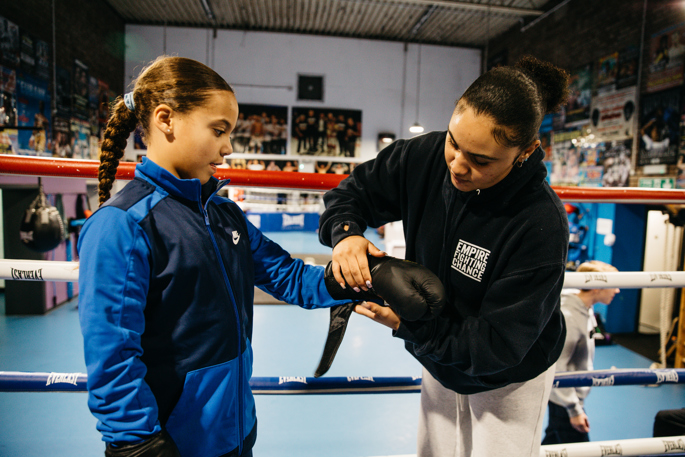 Serena helping a young person put on their boxing gloves